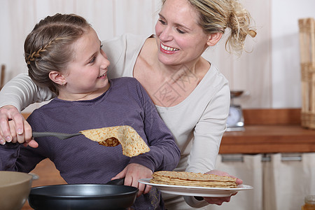 母亲和女儿享受烹饪煎饼的乐趣图片
