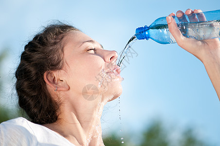 美丽的妇女饮用水 干渴女性跑步蓝色运动瓶子流动口渴成人重量快乐图片