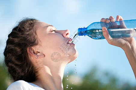 美丽的妇女饮用水 干渴运动员瓶子蓝色快乐矿物火车女性有氧运动流动天空图片