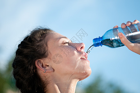 美丽的妇女饮用水 干渴闲暇矿物天空活力火车瓶子女士运动员慢跑蓝色图片