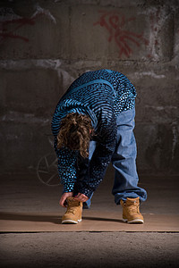 在砖墙上跳现代风格的Hipop舞者情感夜生活说唱演员特技运动女孩黑发街道牛仔裤图片