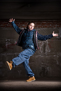 在砖墙上跳现代风格的Hipop舞者蓝色演员特技黑发运动培训师街道说唱青少年衣服图片
