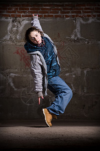 在砖墙上跳现代风格的Hipop舞者舞蹈家衣服说唱运动女孩霹雳舞培训师牛仔裤街道特技图片