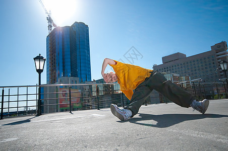 在城市风景中跳舞的青少年嘻哈女孩裤子靴子特技空气橙子射线自由房子运动光束图片