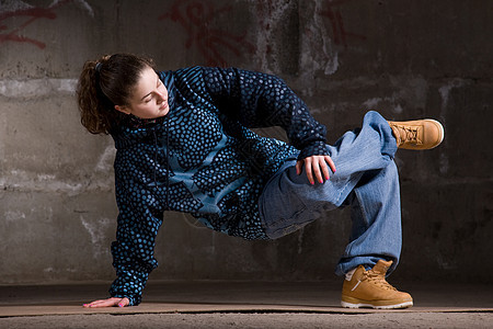 在砖墙上跳现代风格的Hipop舞者女孩舞蹈家女士夜生活黑发运动培训师街道特技衣服图片