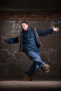 在砖墙上跳现代风格的Hipop舞者运动蓝色情感青少年牛仔裤黑发培训师靴子霹雳舞衣服图片