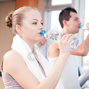 在体育馆运动后饮用饮用水的男女瓶子男人身体女士训练女孩福利教练俱乐部微笑图片