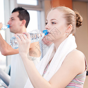 在体育馆运动后饮用饮用水的男女运动装活力健身房闲暇跑步机瓶子俱乐部毛巾跑步有氧运动图片