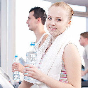在体育馆运动后饮用饮用水的男女有氧运动教练训练运动装健身房活力中心男人毛巾福利图片