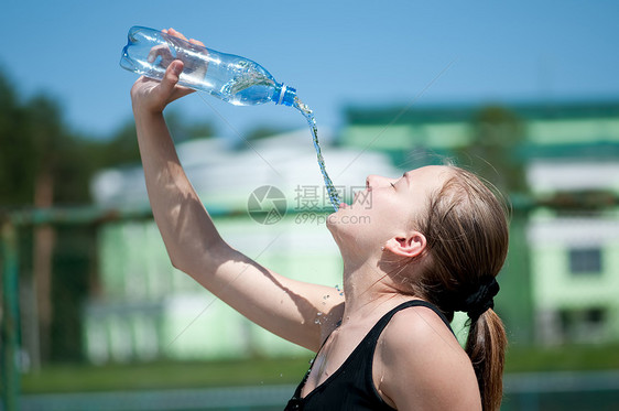 年青妇女锻炼后饮用饮用水天空运动员蓝色太阳闲暇成人瓶子女性活力矿物图片