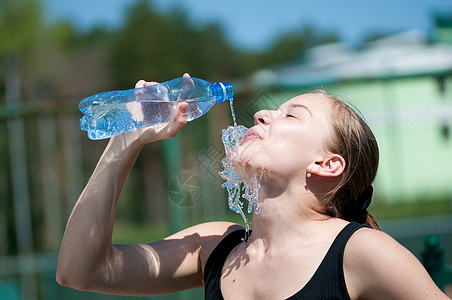 年青妇女锻炼后饮用饮用水长发女孩天空闲暇运动运动员瓶子青少年太阳深色图片