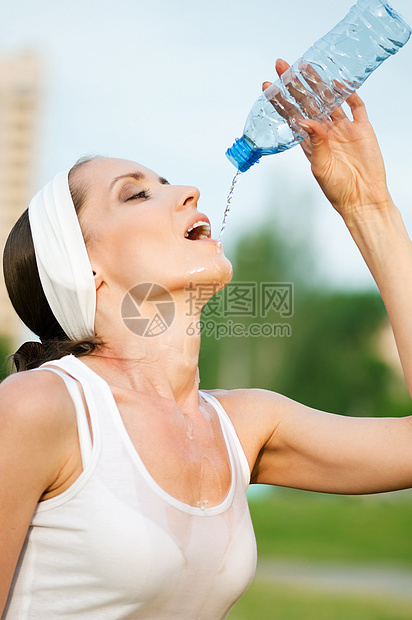 户外运动中的妇女饮用水天空运动装公园成人蓝色火车矿物卫生瓶子女性图片