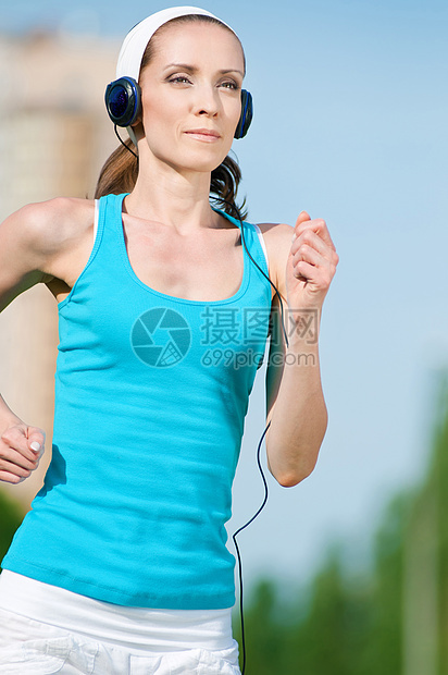 美丽的女子在绿色公园中奔跑肌肉身体公园训练女性赛跑者女士跑步耳机慢跑者图片