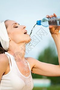 户外运动中的妇女饮用水慢跑瓶子公园矿物成人赛跑者跑步流动女性运动装图片