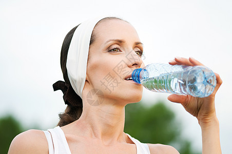 户外运动中的妇女饮用水流动保健成人行动运动员天空运动蓝色慢跑女士图片