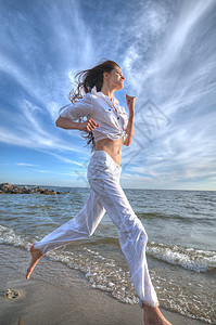 运动妇女跑在海上海岸天空闲暇太阳海滩日落跑步女士自由活动女性图片