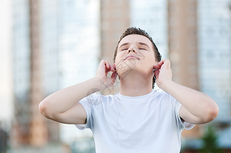 有耳机的有吸引力的年轻人公园快乐喜悦青少年青年音乐蓝色闲暇男生城市图片