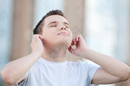 有耳机的有吸引力的年轻人自由街道蓝色男生快乐青少年天空男性公园娱乐图片