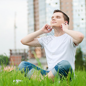 有耳机的有吸引力的年轻人音乐青少年闲暇男生自由街道男人天空美丽日光浴图片