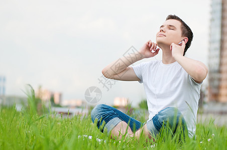 有耳机的有吸引力的年轻人快乐自由男性美丽男人天空公园音乐街道闲暇图片