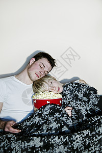 年轻夫妇在看电视沙发娱乐午睡家居两个人床单爆米花睡眠客厅电影图片