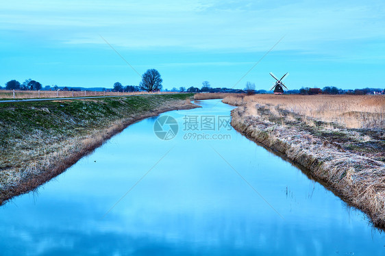 黄昏时的风车和河图片