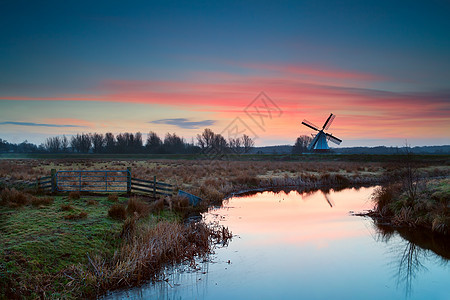 荷兰风车和河流上的粉色日出图片