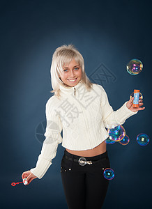 美丽的女人吹着肥皂泡泡金发肥皂水圆圈自由乐趣活动女性色彩俏皮蓝色图片