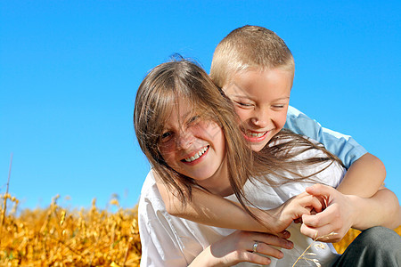 哥哥和姐姐幸福拥抱童年阳光蓝色小伙子天空青年乐趣夫妻图片