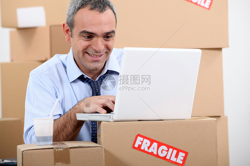 使用膝上型电脑的仓库管理员搬迁互联网笔记本快乐微笑送货盒子纸板包装电讯图片