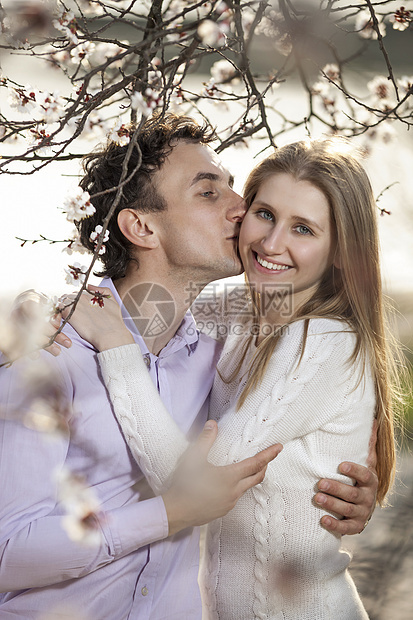 年轻浪漫情侣在春花中拥抱图片