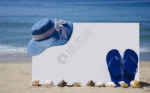 白板 在沙沙滩上挂着翻拖鞋和帽子图片