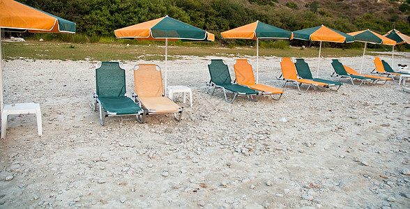沙滩休息椅在雨伞的阴影下图片