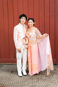 与鲜花加兰合著的 泰国结婚西装 中的亚洲泰新婚新娘女朋友花环丈夫婚礼戏服文化粉色灵魂幸福传统图片