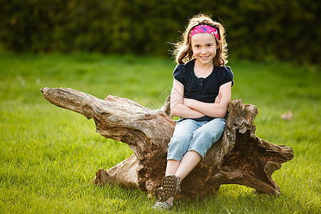坐在树干上的女孩太阳女性微笑黄金时段孩子童年图片