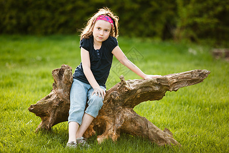 坐在树干上的女孩女性微笑黄金童年太阳时段孩子图片