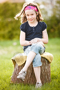 坐在树干上的女孩女性微笑孩子黄金童年太阳时段图片