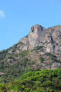 香港的狮子岩石山绿色植物爬坡喇叭草地蓝色天空岩石图片