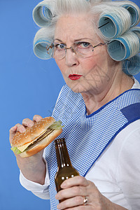 头发里有卷卷发的老人 喝酒喝啤酒吃汉堡包图片