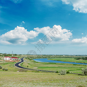 绿色绿地 沥青路和蓝天空以及云彩图片