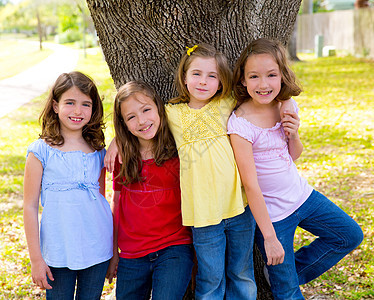 儿童团体朋友女孩在树上玩耍童年女孩们拥抱孩子们草地冒充朋友们蓝色双胞胎友谊图片