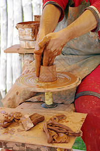 以陶器的手 在圆上创造一个土罐作坊女士手工专注手指工作拇指旋转壤土花瓶图片
