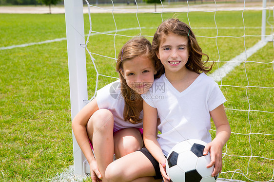 在球场上踢足球的孩子女孩公园爱好足球朋友们草地喜悦微笑金发团队假期图片