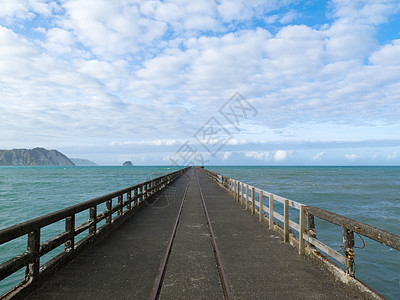托拉加湾码头是新西兰最长的码头历史性蓝色绿色沿海海岸线悬崖海洋多云海景天空图片