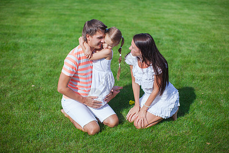 三个年轻三口的家庭坐在草地上 玩得开心图片