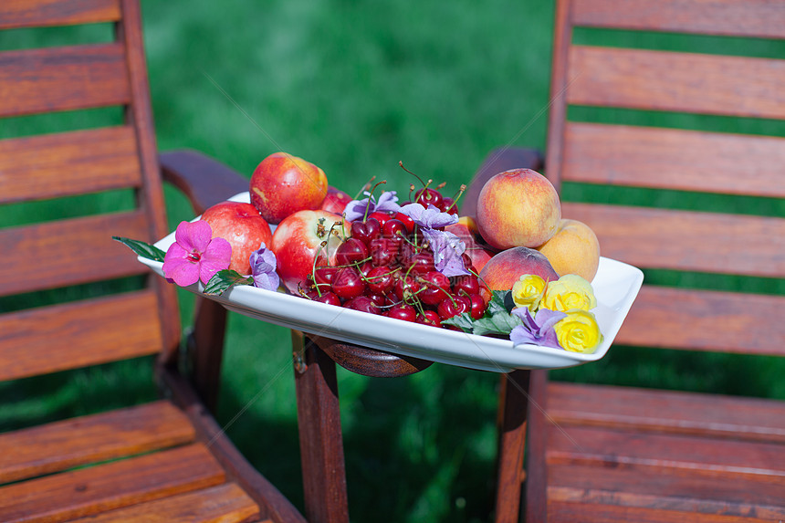 在花园的木制椅子上用新鲜水果和鲜花盘李子甜点静物盘子雏菊美术院子浆果木头食物图片
