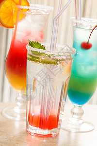 酒吧里鸡尾酒绿色蓝色水果玻璃稻草叶子红色液体柠檬橙子图片