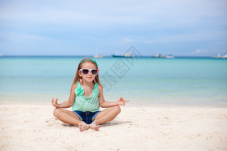 美丽的小女孩坐在异国海滩上的莲花沙滩上幸福孩子海岸假期头发海洋自由支撑童年女孩图片