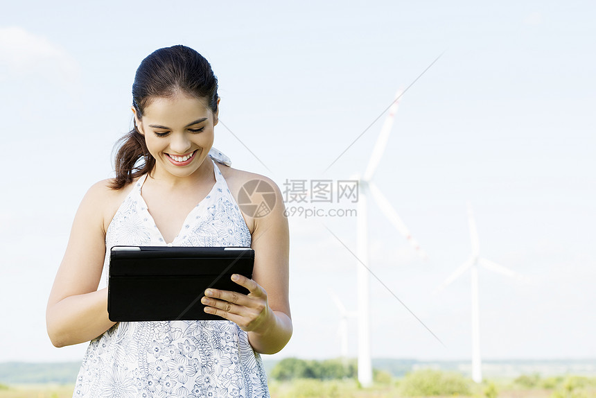 在风力涡轮机旁边有平板电脑的少女互联网生态天空女孩活力场地药片邮件技术涡轮图片