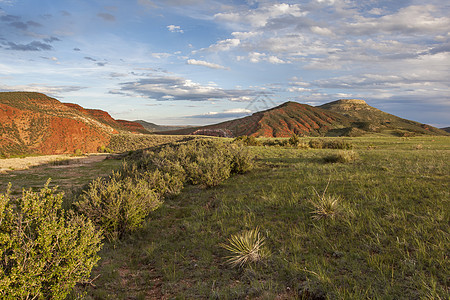 山山牧场前端草原崎岖石头草地红色悬崖绿色范围图片